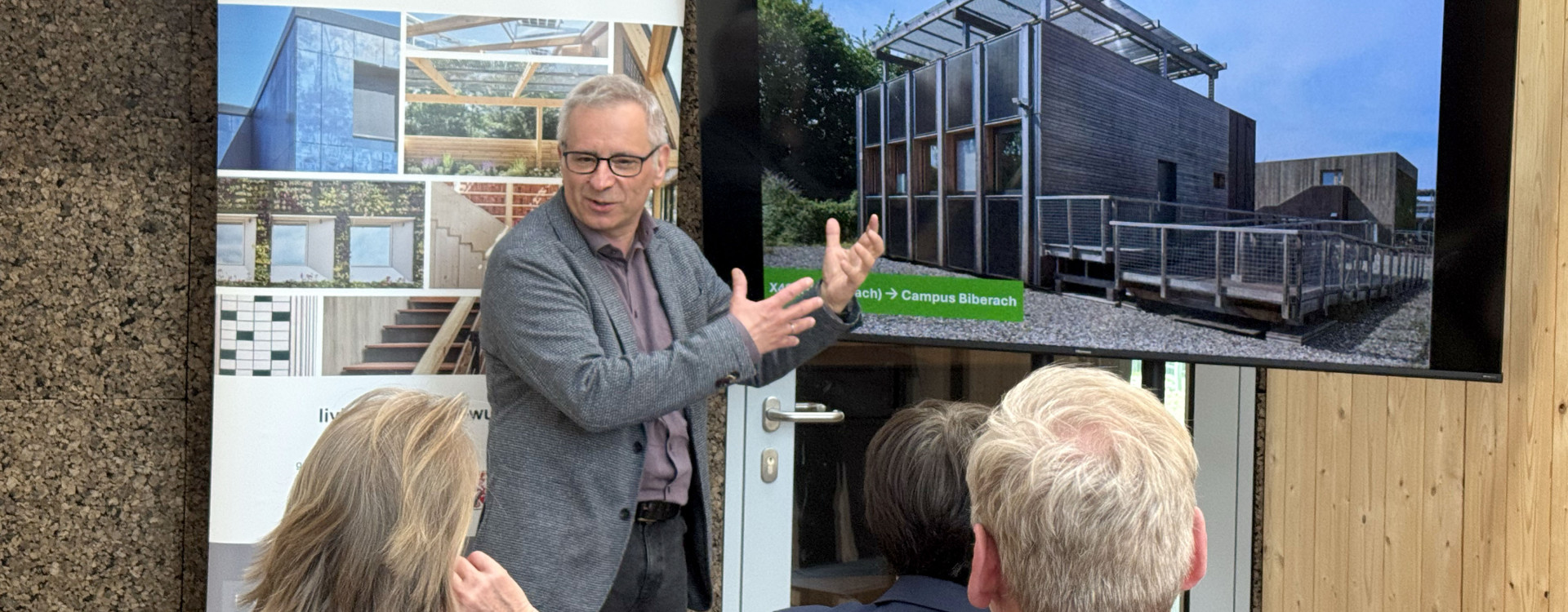 Ein Mann steht vor einem Bildschirm und erklärt etwas