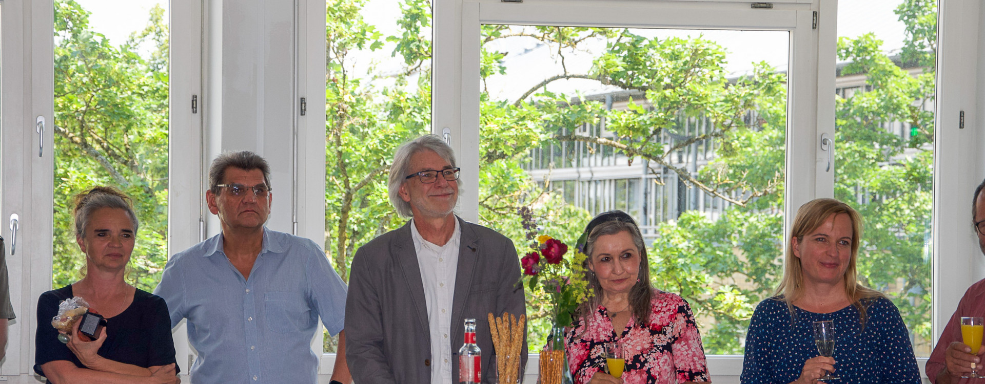 Fünf Erwachsene stehen in einer Reihe bei einer festlichen Veranstaltung