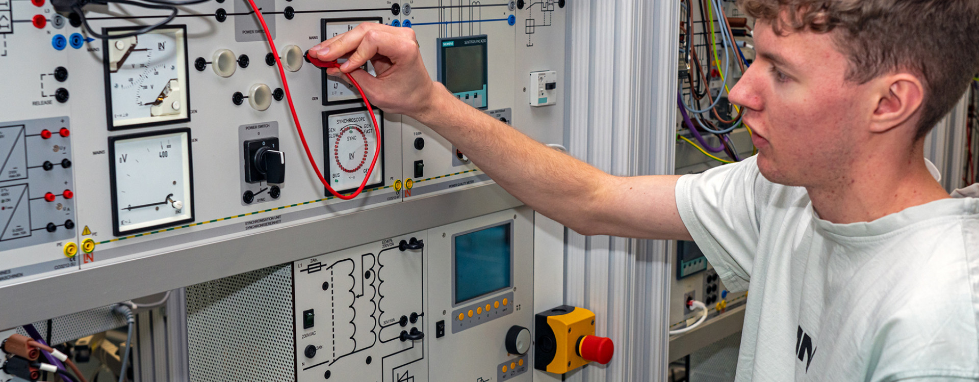 Studierender Jens Hagmeyer steht vor Modell Netzsynchronisation im Labor für Elektrische Systeme