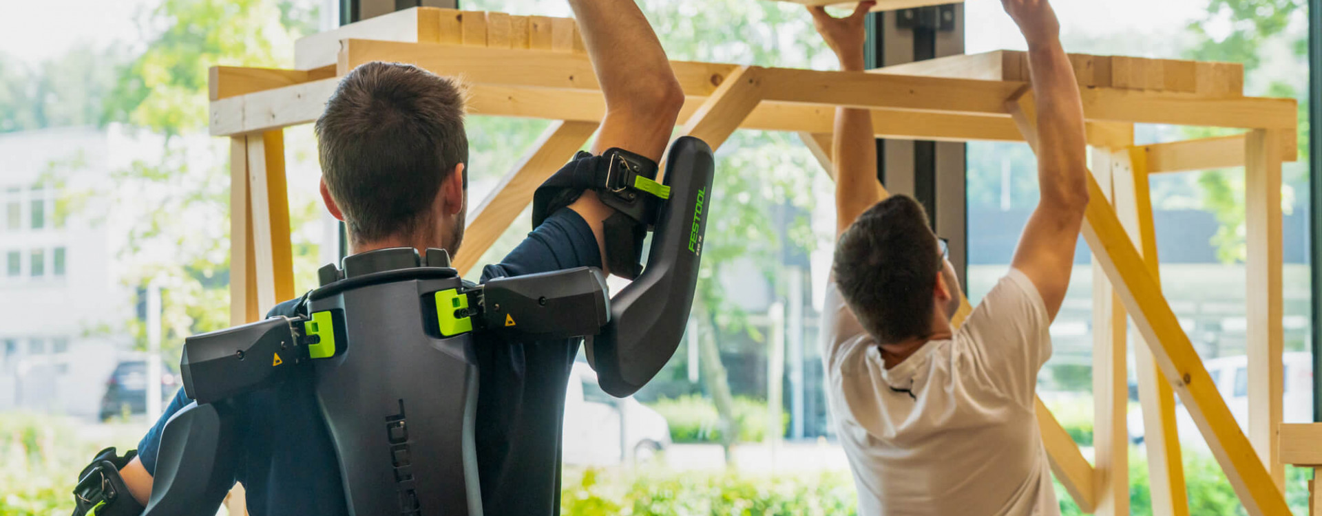 Zwei Studierende arbeiten Überkopf mit Exoskelett