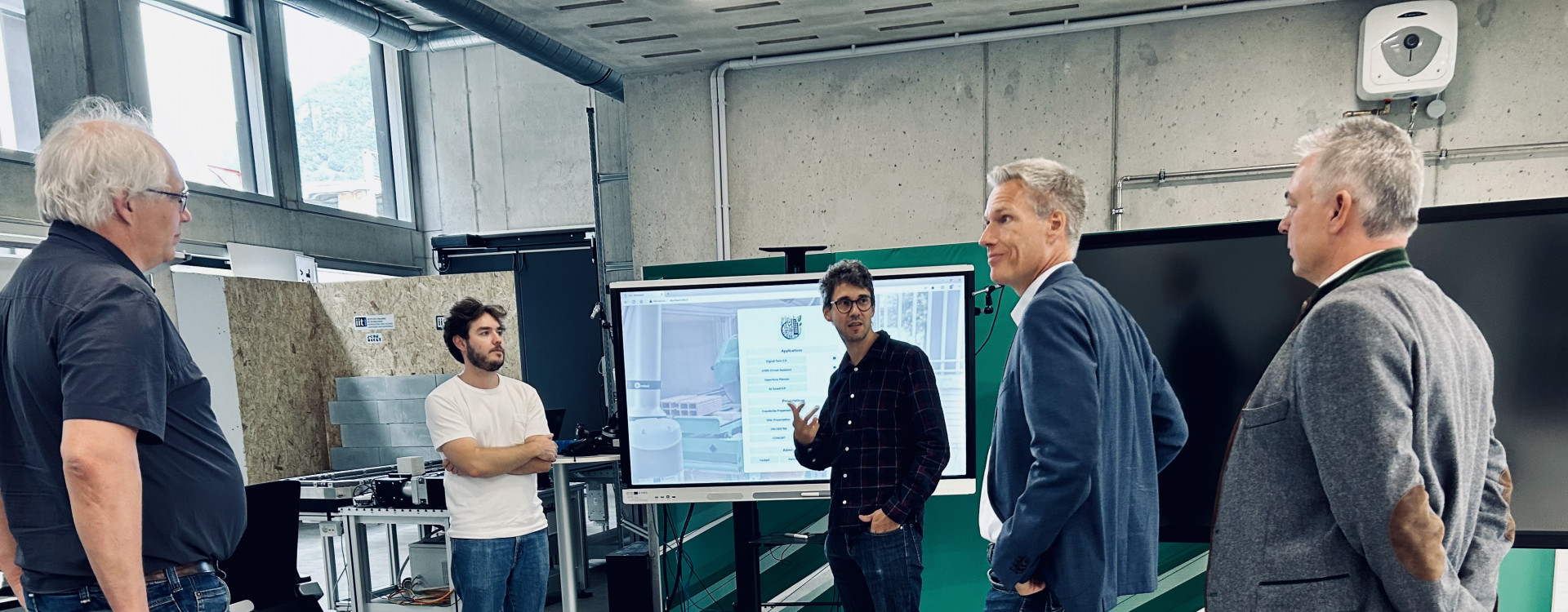 Fünf Männer stehen in einem Raum und diskutieren