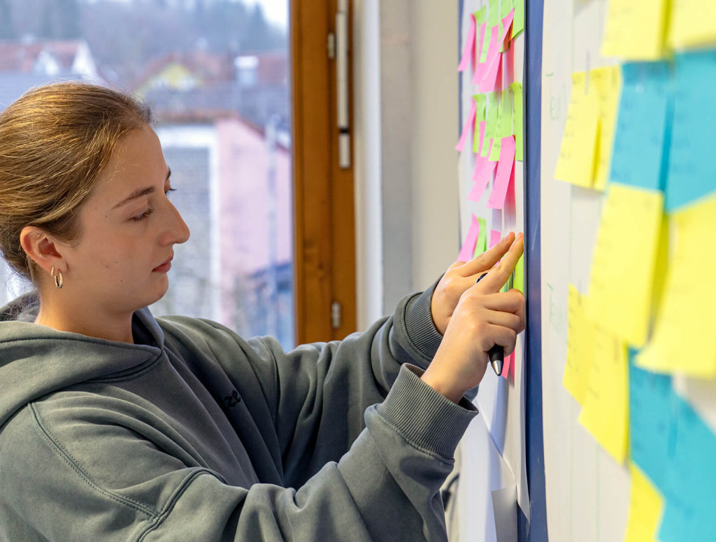 Eine Studierende sortiert Post-Its an der Wand um sich einen Überblick zum Thema SAP zu verschaffen