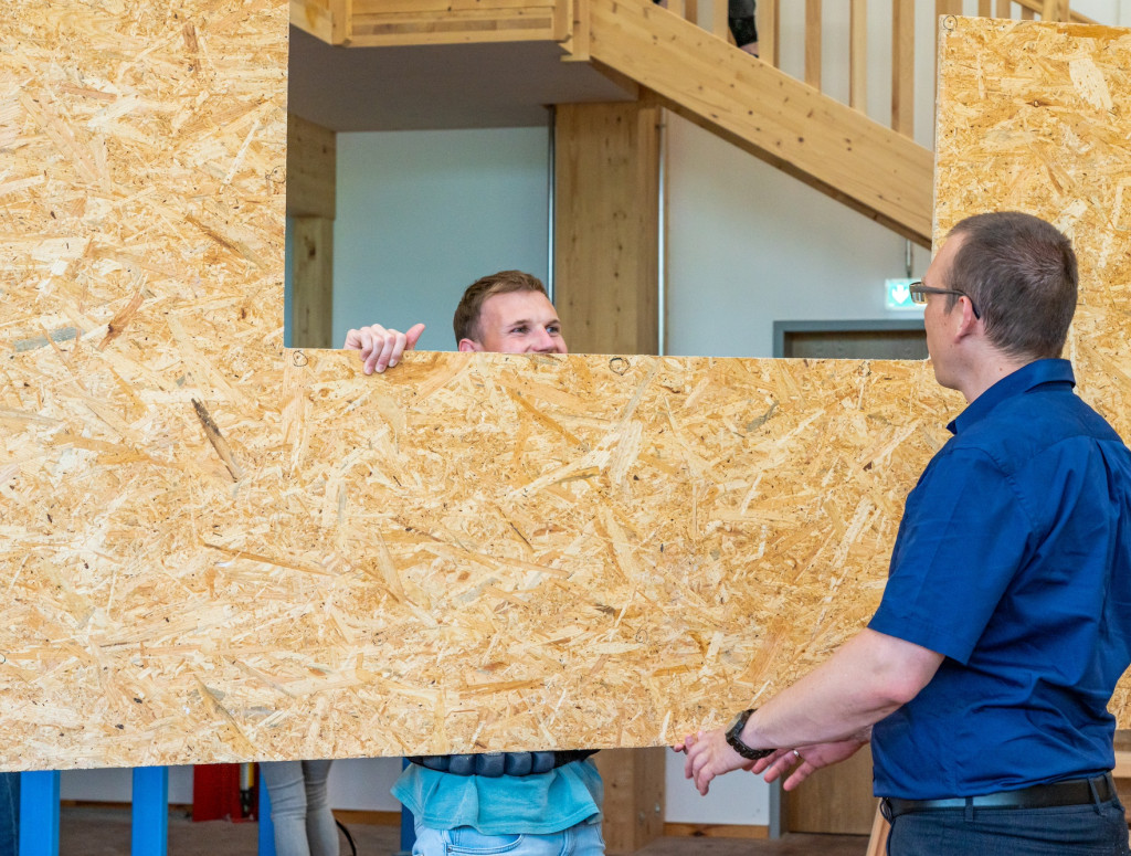Zwei Männer tragen eine Holzwand