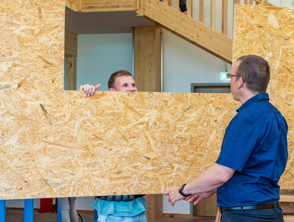 Zwei Männer tragen eine Holzwand