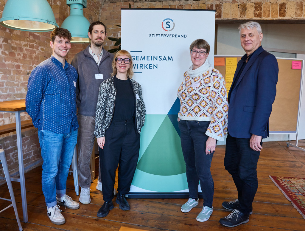 Fünf Personen stehen vor einem Banner