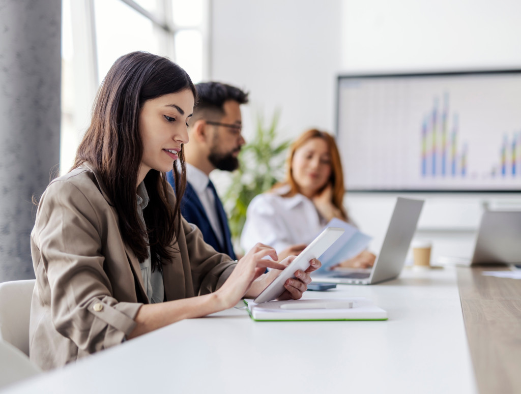 Drei Personen sitzen mit Laptops an einem Tisch