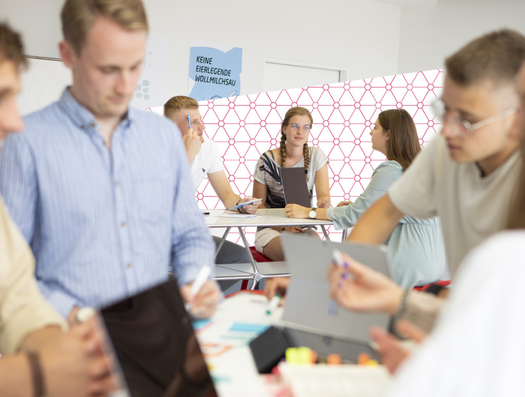 Personen in einem Raum arbeiten an Tischen