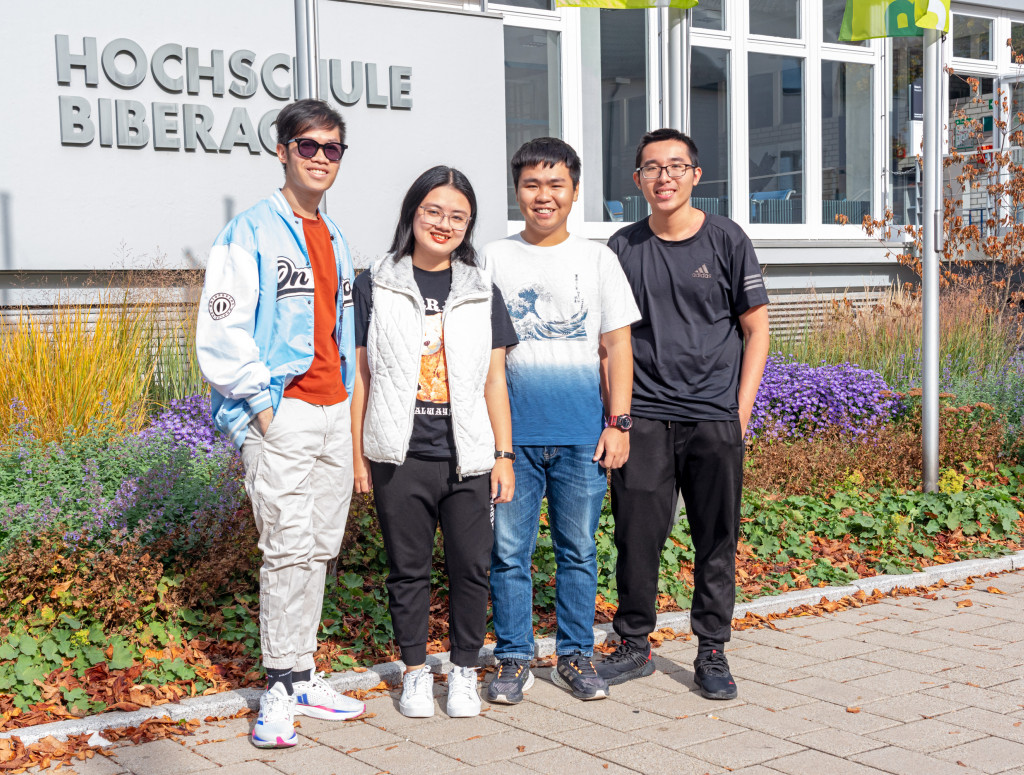 Studierende aus Vietnam stehend vor HBC-Schriftzug