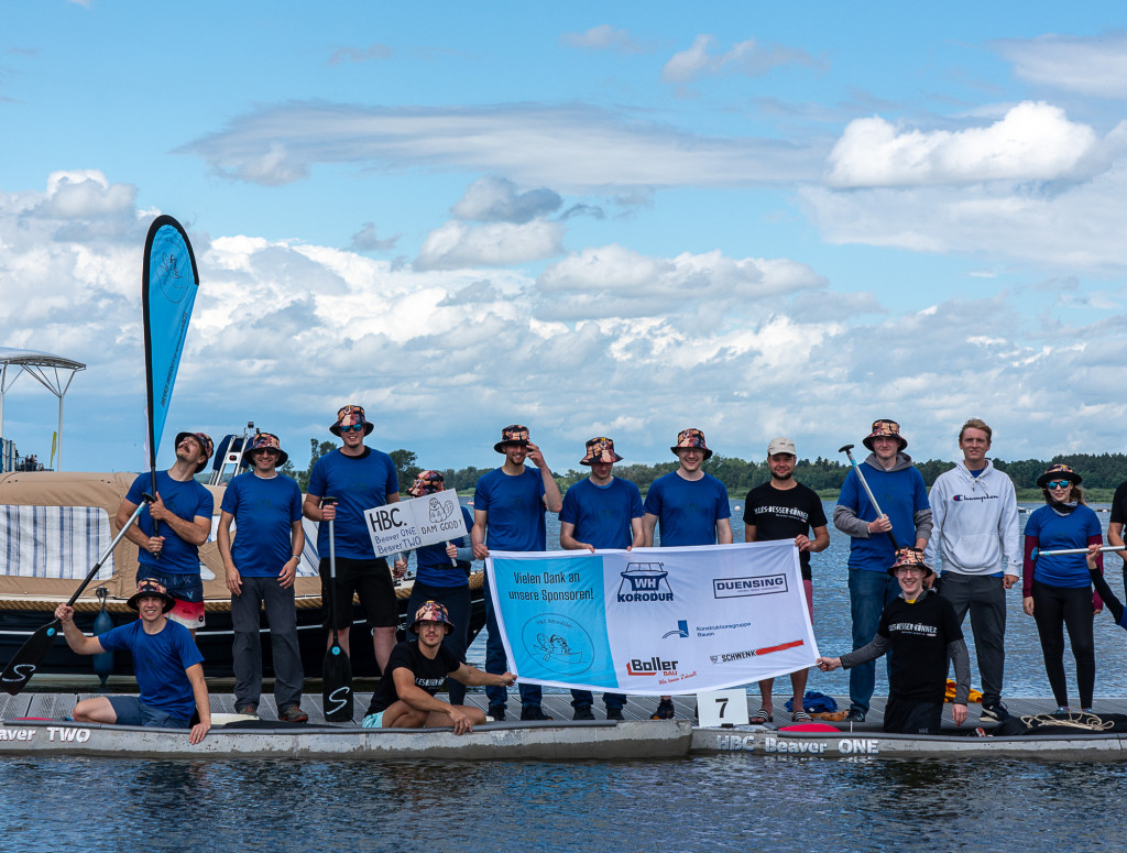 Viele Personen stehen auf einem Steg am Wasser