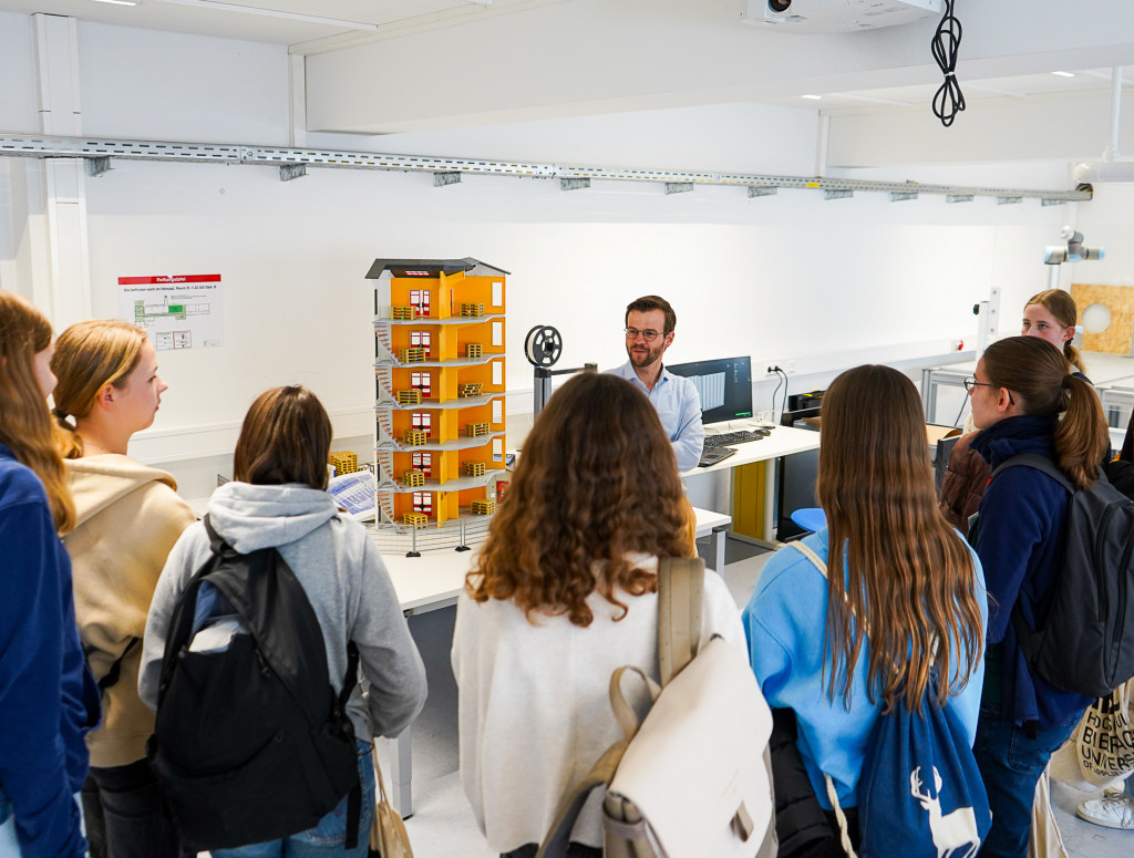 Schülerinnen stehen im Labor und hören Professor zu