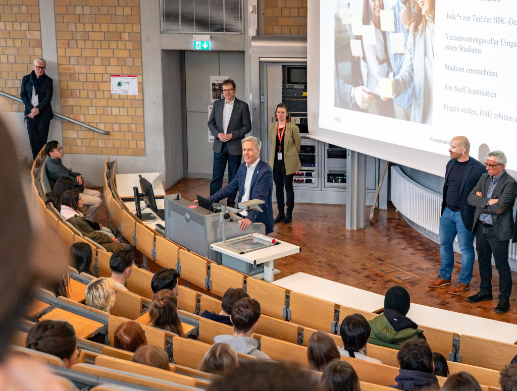 Prof. Bahr steht im Hörsaal und begrüßt Studierende