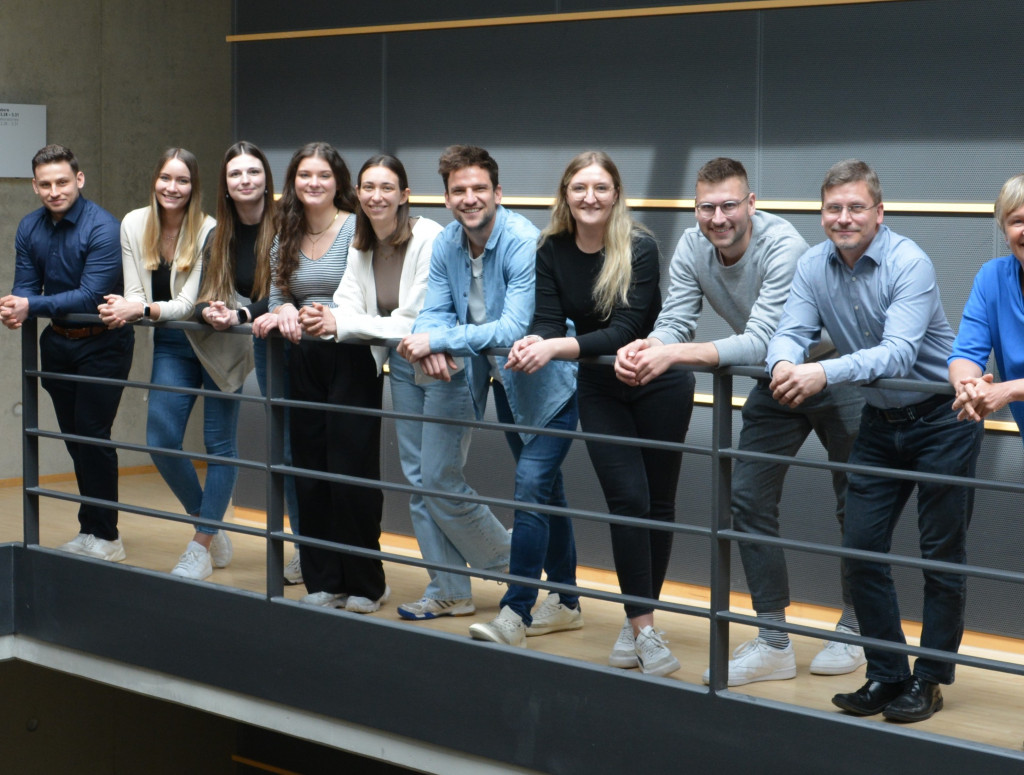 Gruppe von Menschen lehnt an Stahlgeländer in Treppenhaus