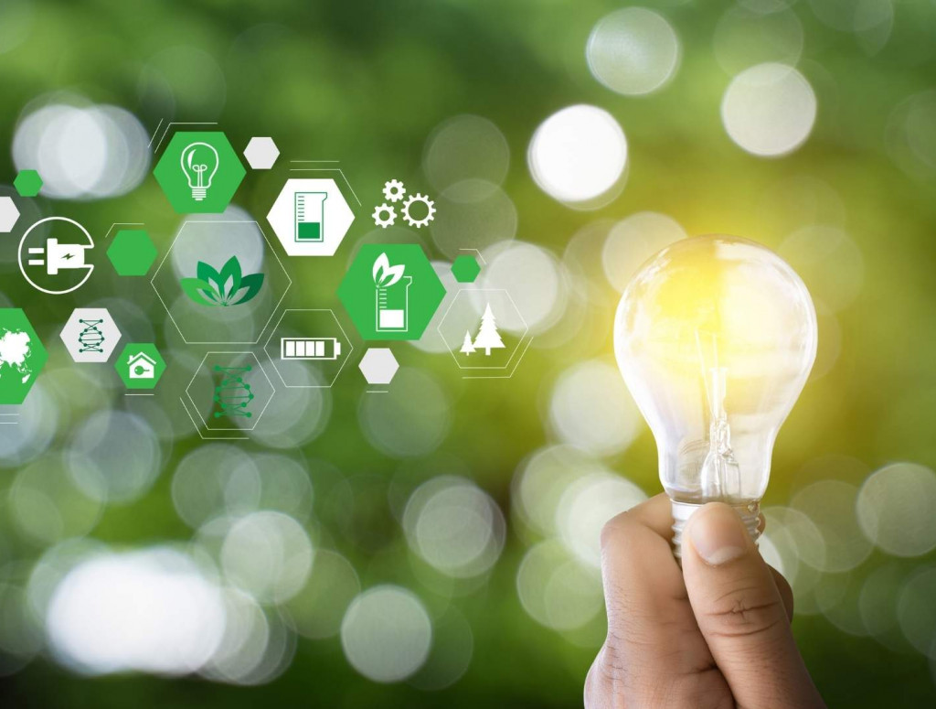 Eine Hand hält eine Glühbirne vor einem grünen Hintergrund, rechts davon sind mehrere kleine Icons rund um das Thema Energie und Nachhaltigkeit zu sehen