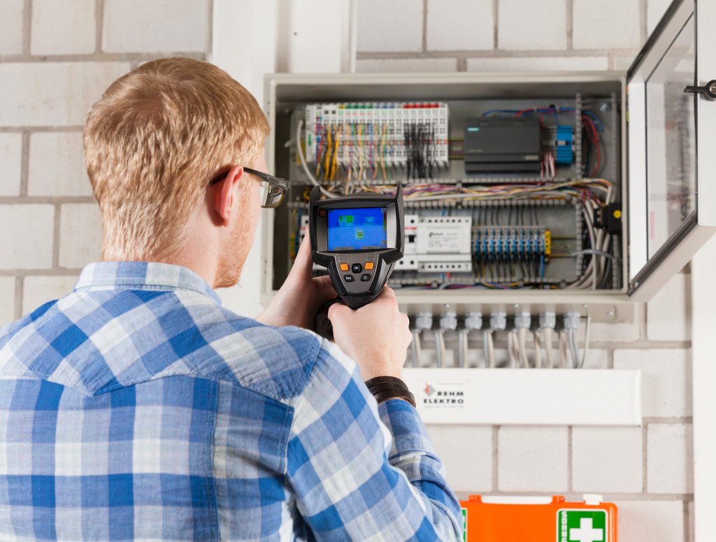 Student mit Ablesegerät vor einem Stromkasten