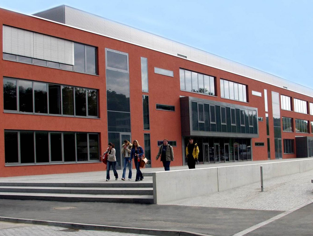 Rotes Gebäude, Schule, mit Personen davor