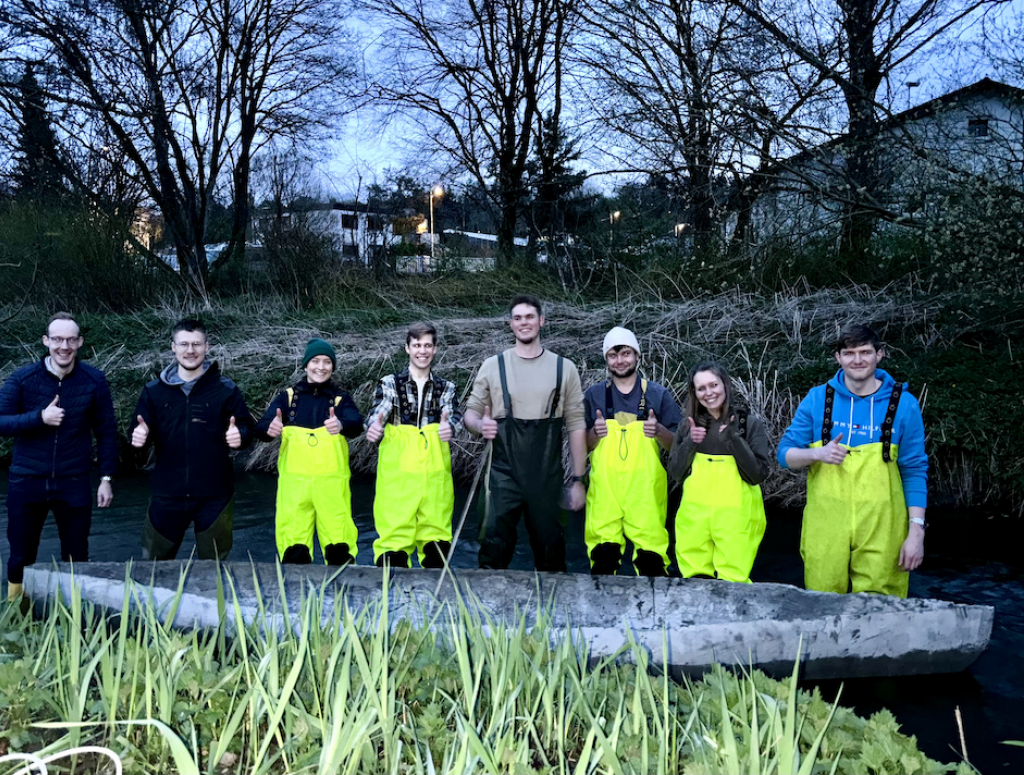 Gruppenbild junger Menschen im Bach mit Betonkanu