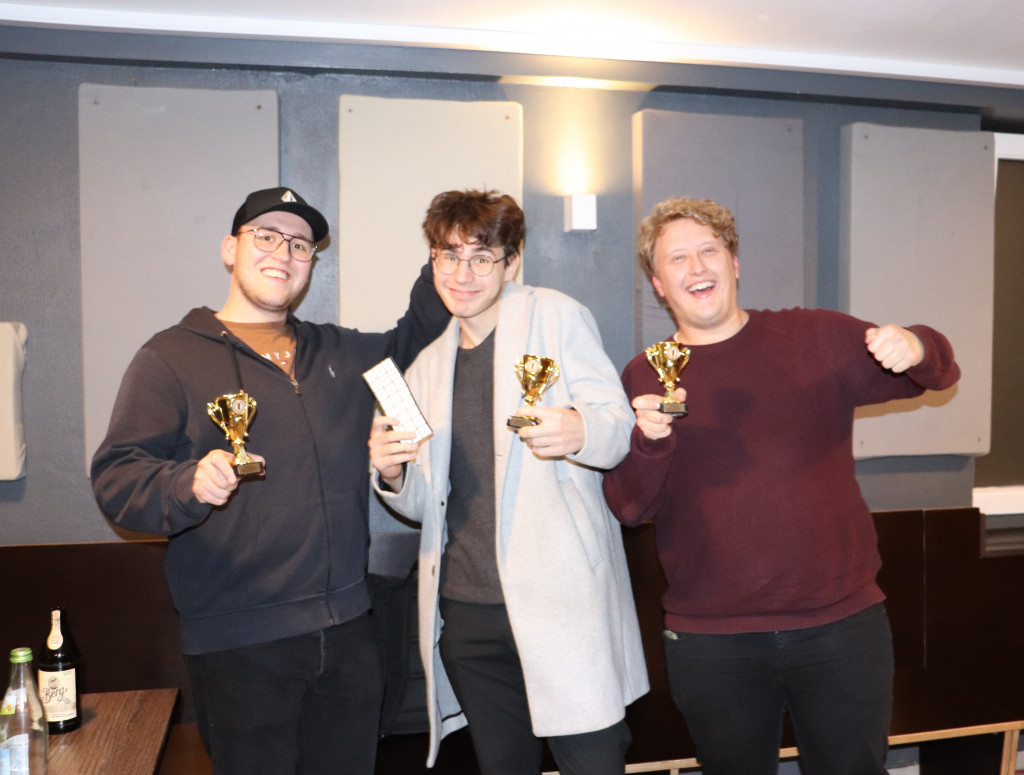Drei Studenten mit Pokalen in der Hand, freuen sich über den Gewinn bei der KI Werkstatt Night