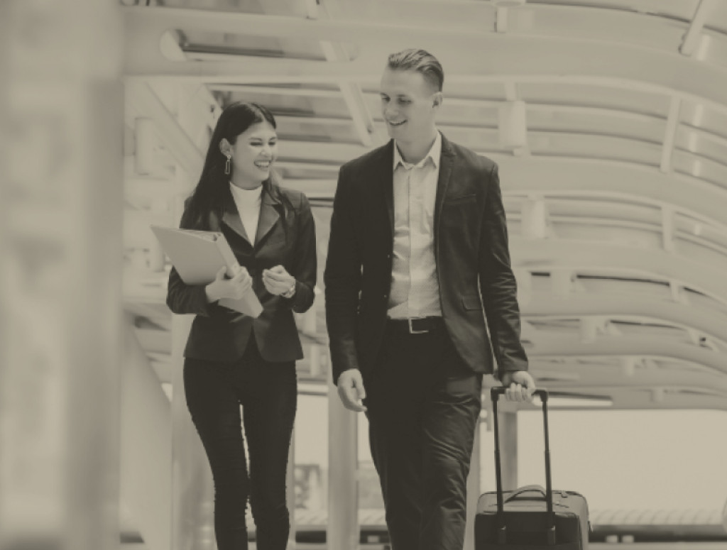 Eine Frau und ein Mann in Businesskleidung mit einem kleinen Koffer