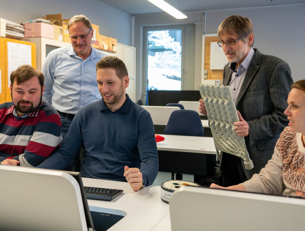 Fünf Mitarbeiter*innen sitzen vor einem Bildschirm