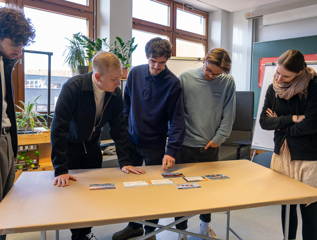 Personen stehen um einen Tisch herum und arbeiten interaktiv