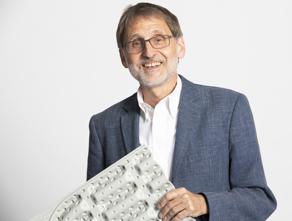 Ein Mann hält etwas in der Hand und lacht in die Kamera