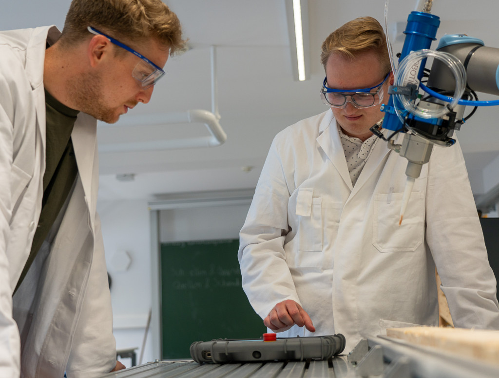 Zwei Männer im Labor arbeiten an einem Roboterarm