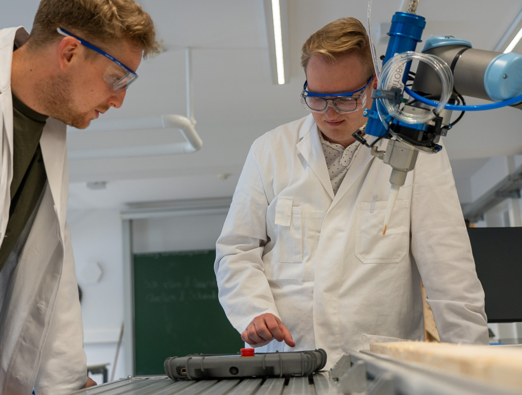 Zwei Männer im Labor arbeiten an einem Roboterarm