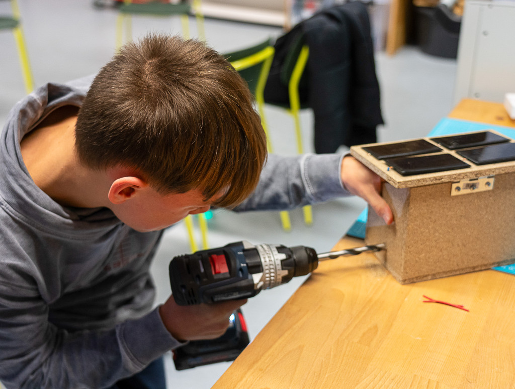 Junge schraubt an Holz