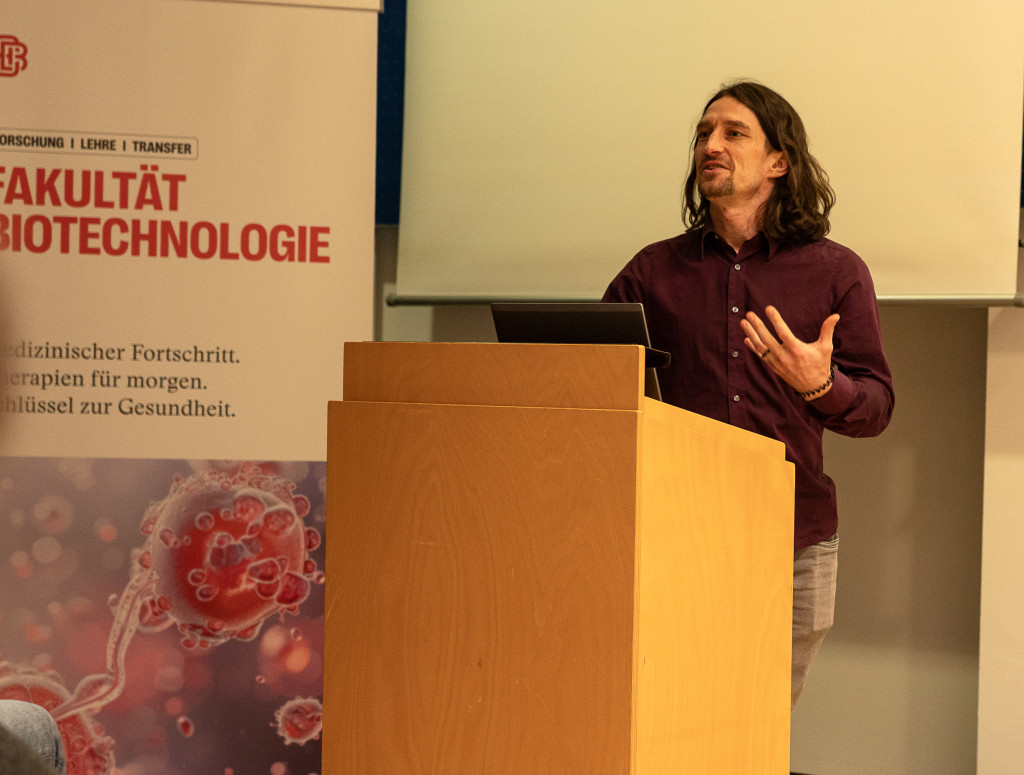 Ein Mann steht vor einem Pult und hält einen Vortrag