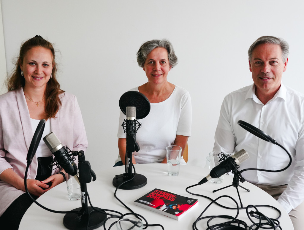 Drei Personen sitzen bei einer Podcast-Aufnahme
