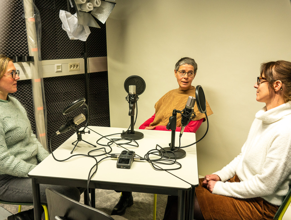 Drei Frauen sitzen bei einem Podcast am Tisch