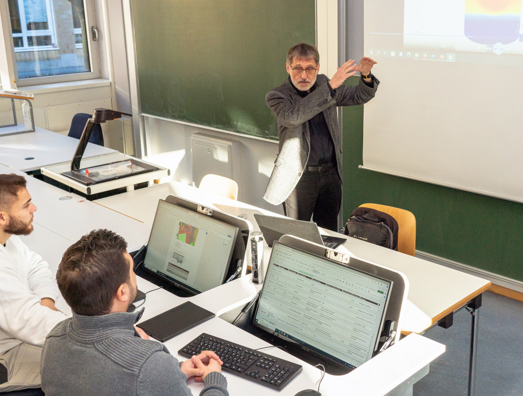 Studierende sitzen in Labor mit hochmodernen Schreibtischen