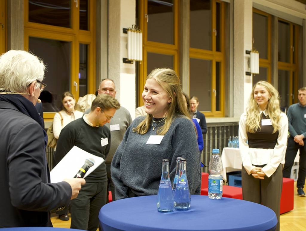 Mann übergibt Urkunde an Studentin