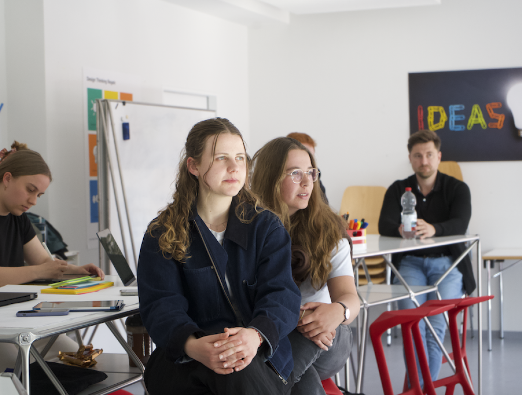 Studierende sitzen an Tischen