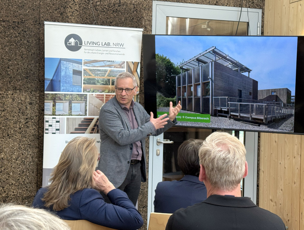 Ein Mann steht vor einem Bildschirm und erklärt etwas