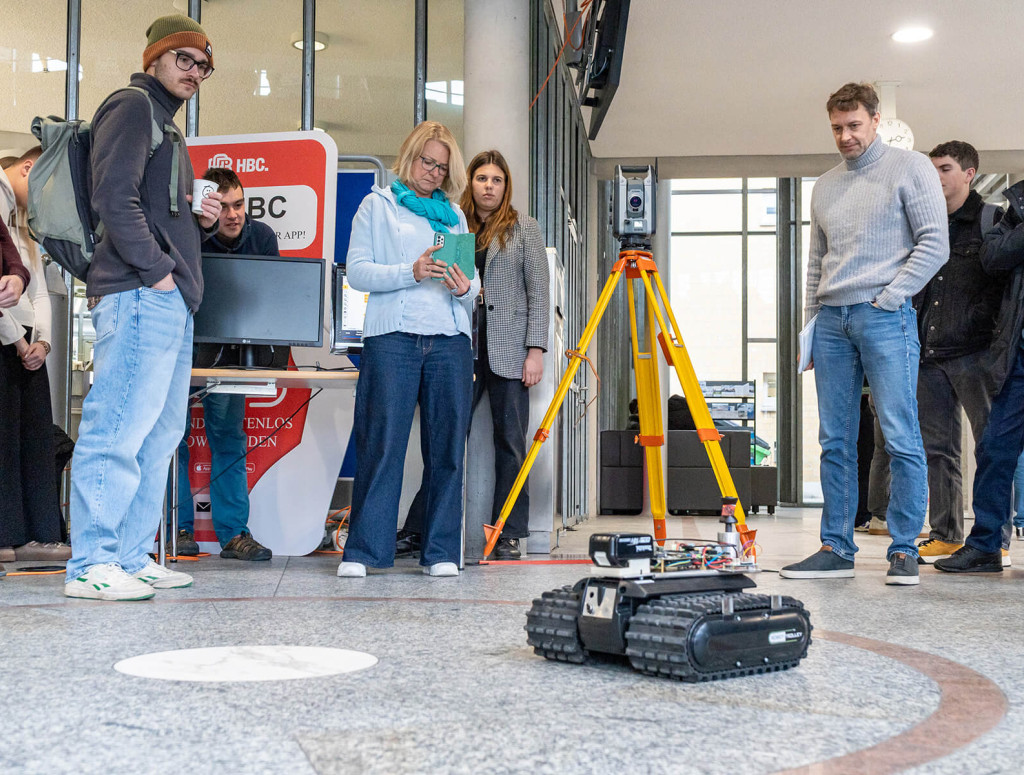 Eine Gruppe Studierender und Professor*innen steuert und filmt einen autonomen Roboter für die Baustelle