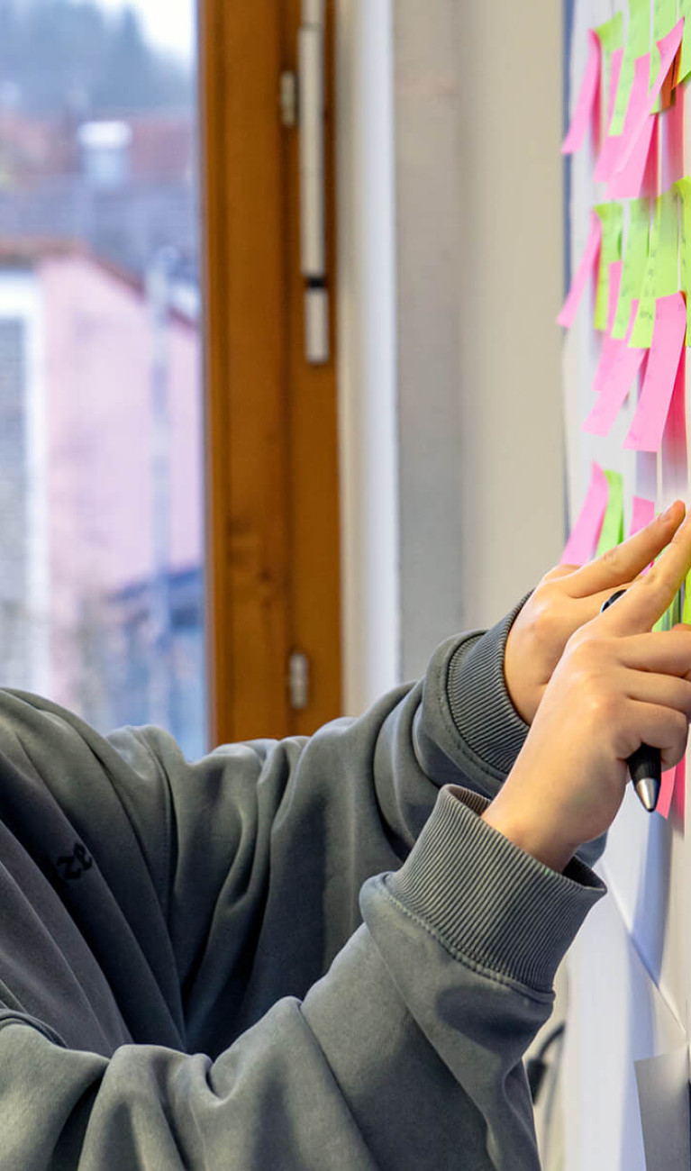 Eine Studierende sortiert Post-Its an der Wand um sich einen Überblick zum Thema SAP zu verschaffen