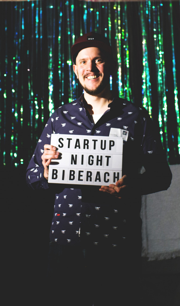 Mann vor glitzerndem Hintergrund mit Schild in der Hand