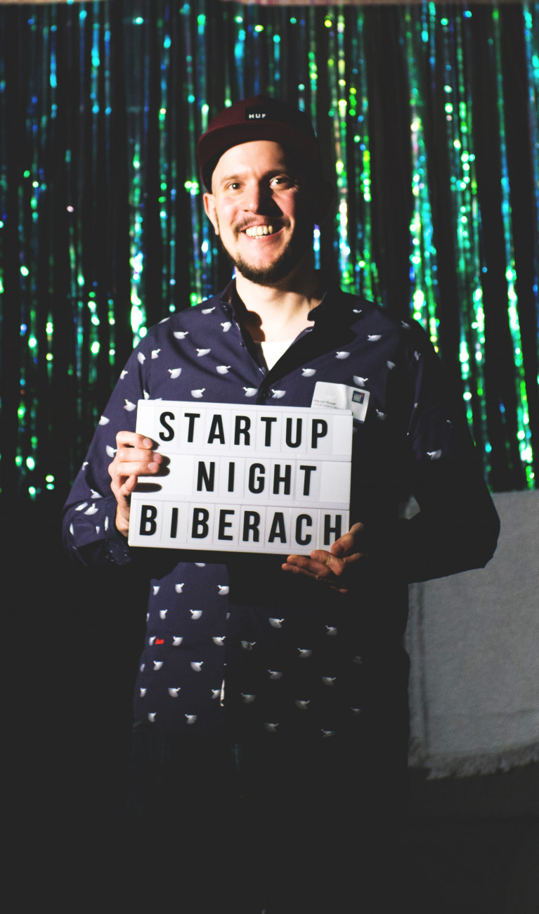 Mann vor glitzerndem Hintergrund mit Schild in der Hand