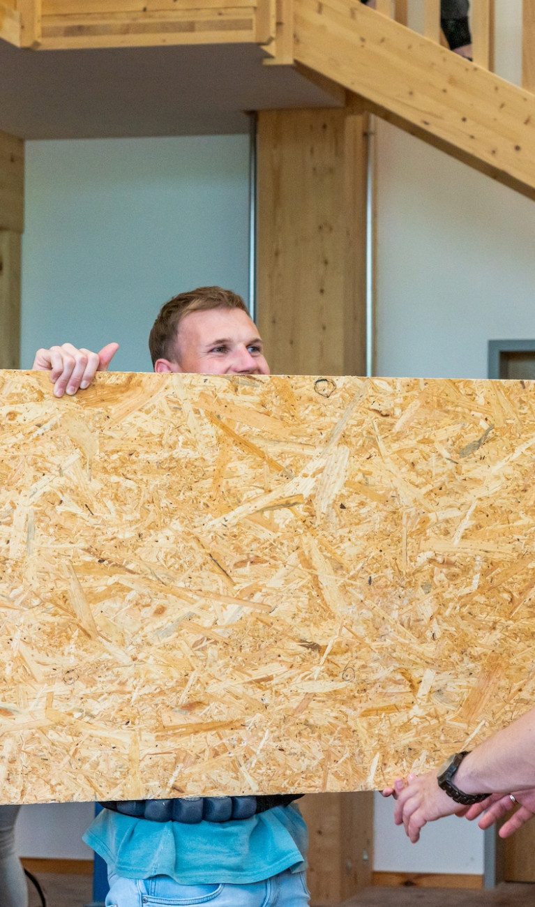 Zwei Männer tragen eine Holzwand