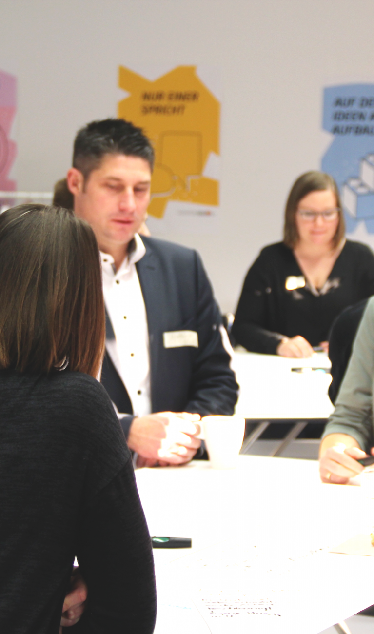 Erwachsene stehen um Tisch herum