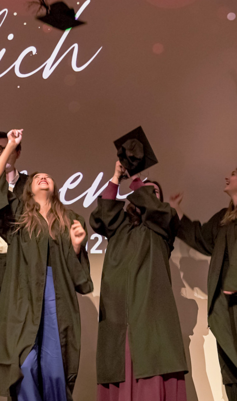 Absolvent*innen werfen Hüte in die Luft