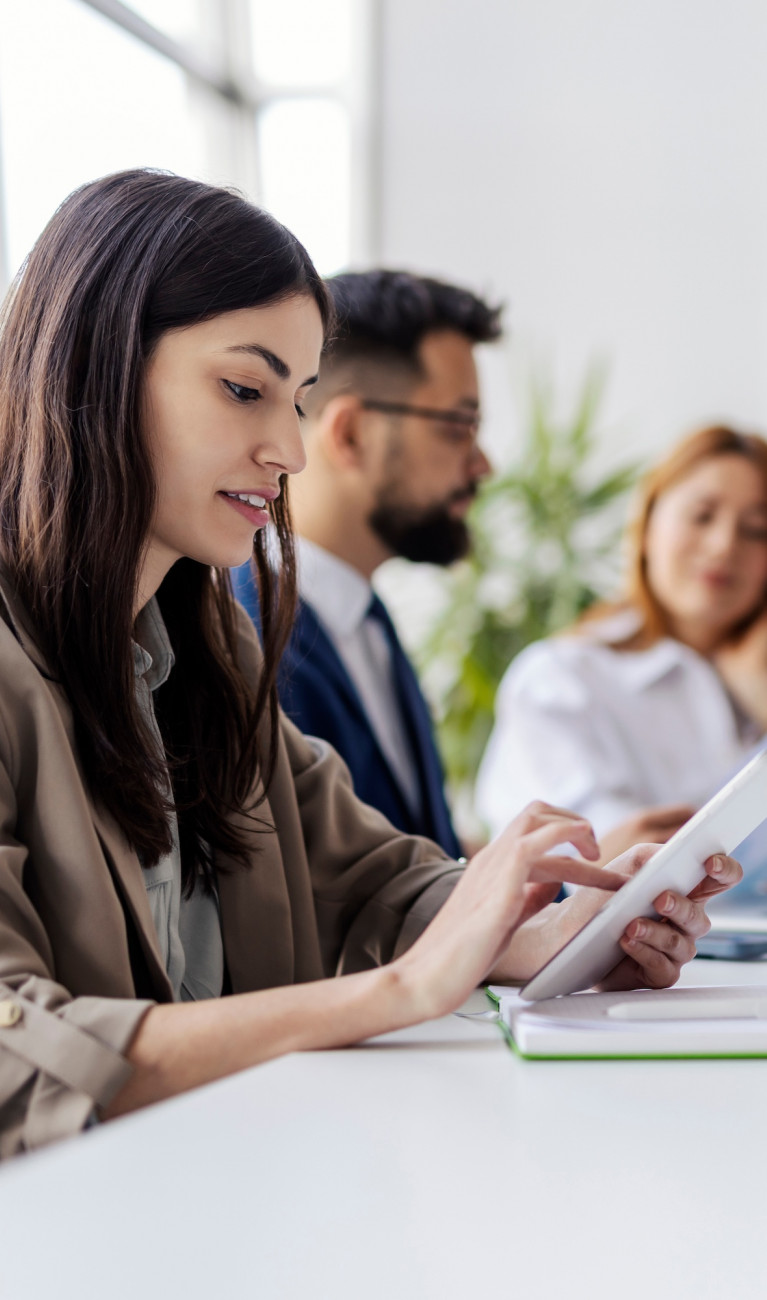 Drei Personen sitzen mit Laptops an einem Tisch