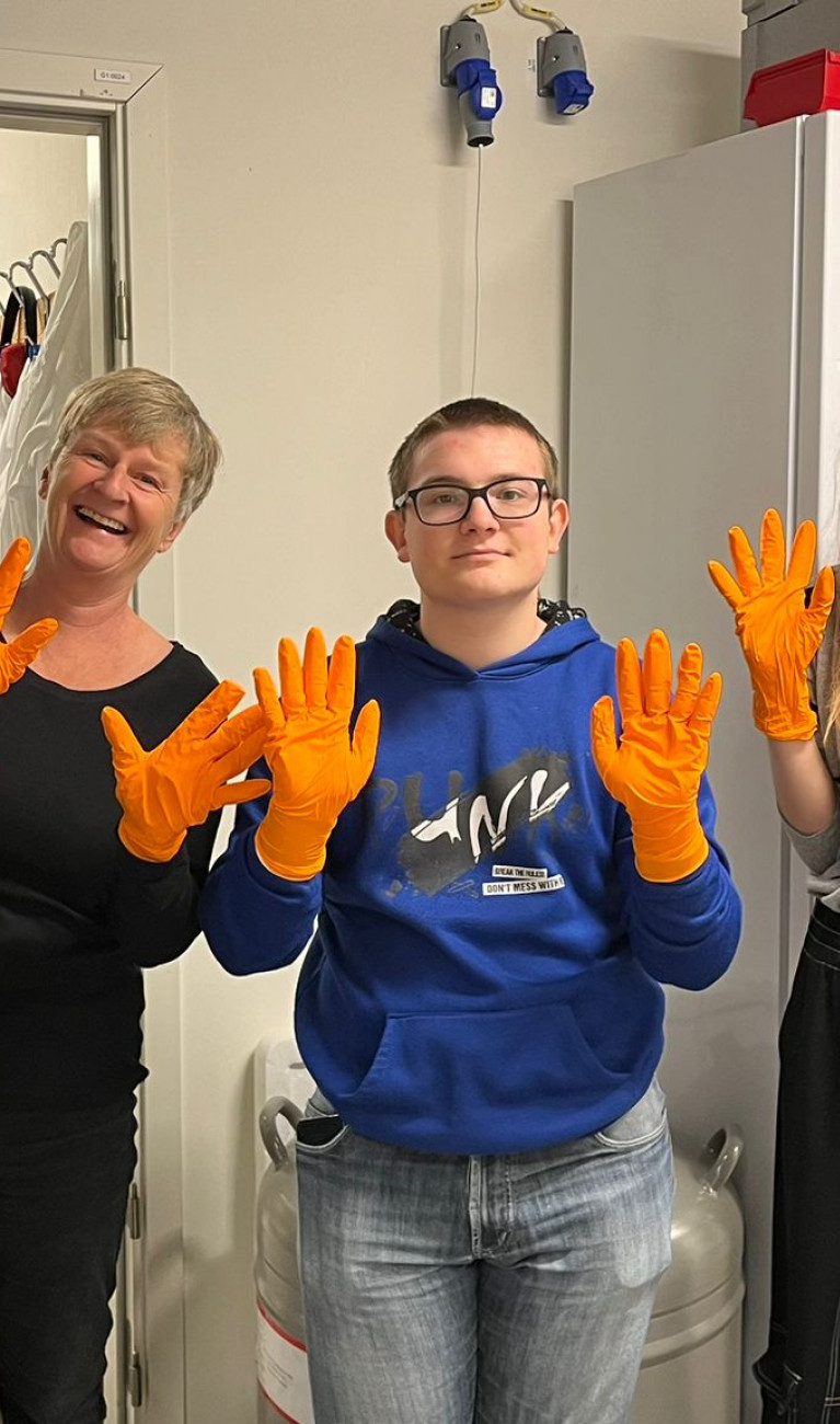 Sechs Personen mit orangen Handschuhen lächeln in die Kamera