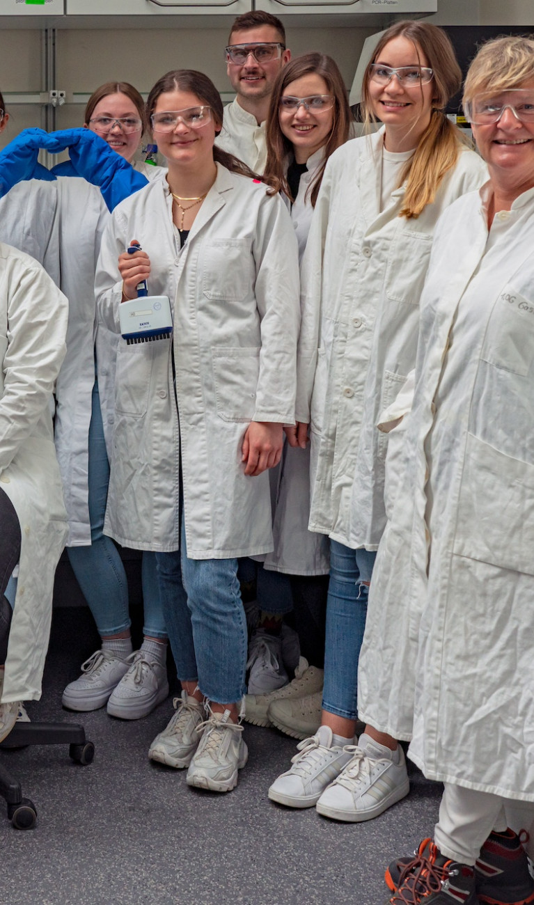 Gruppe von Menschen in Laborkitteln und mit Schutzbrillen