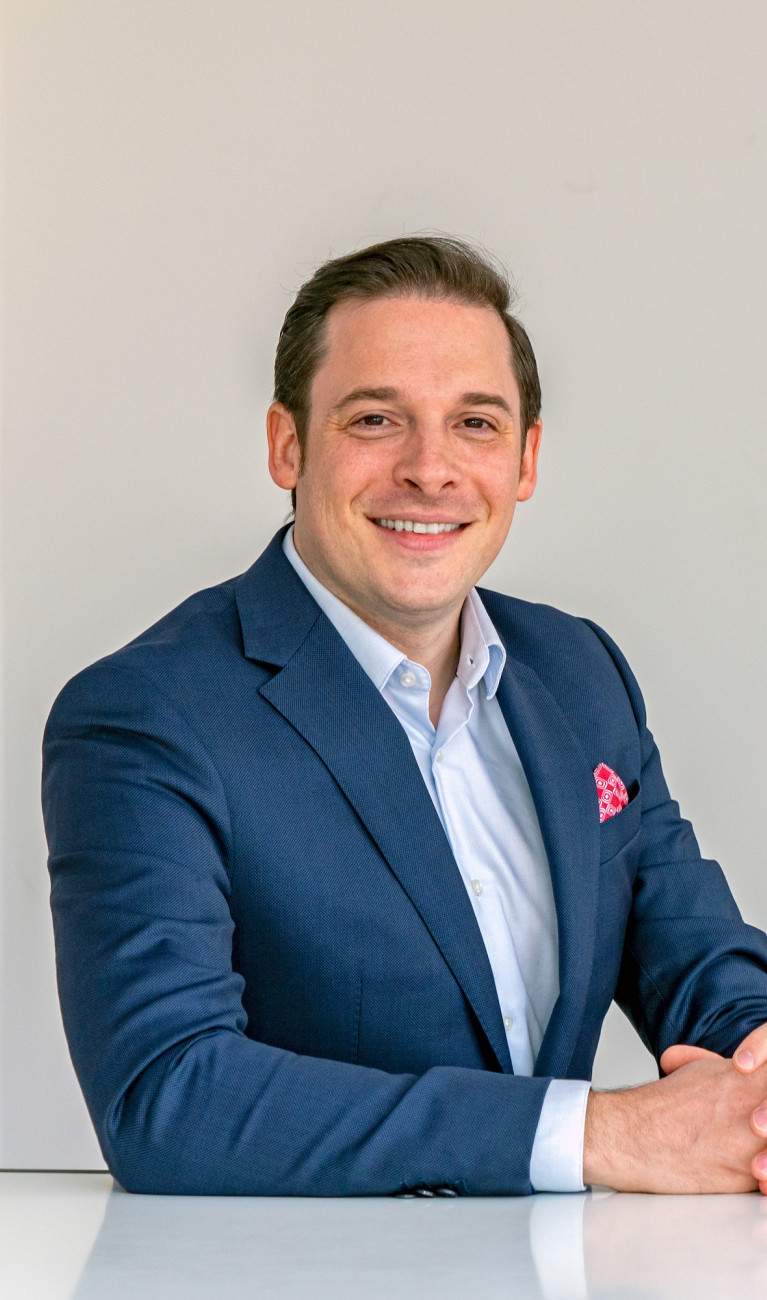 Mann im Anzug sitzt an einem weißen Tisch