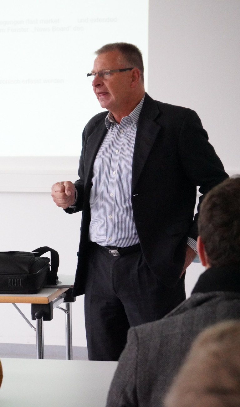 Mann steht vor Studierenden und hält Vortrag