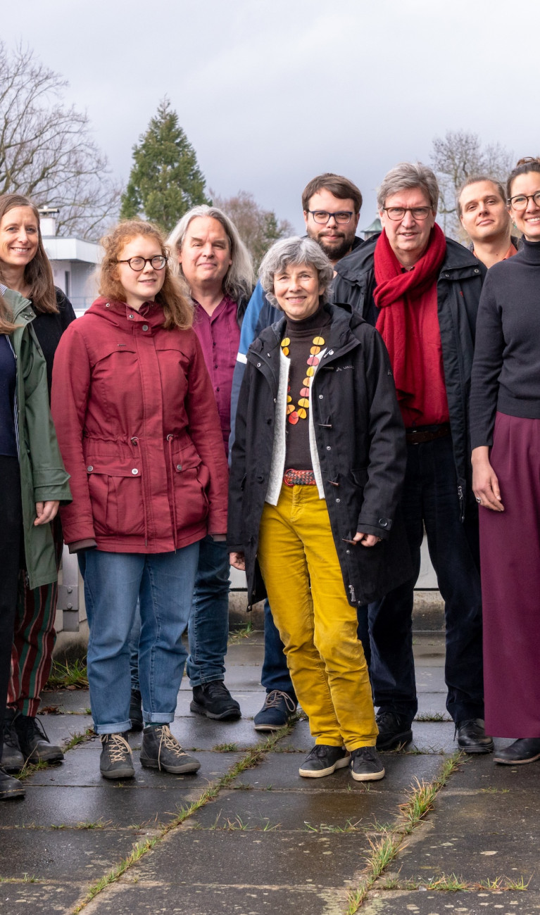 Viele Personen stehen draußen und lachen in die Kamera