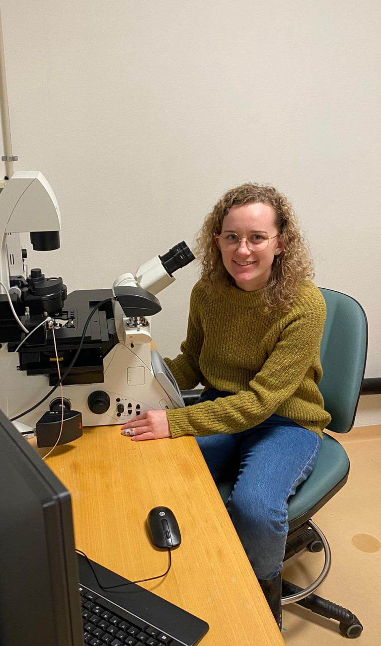 Junge Frau sitzt vor Mikroskop