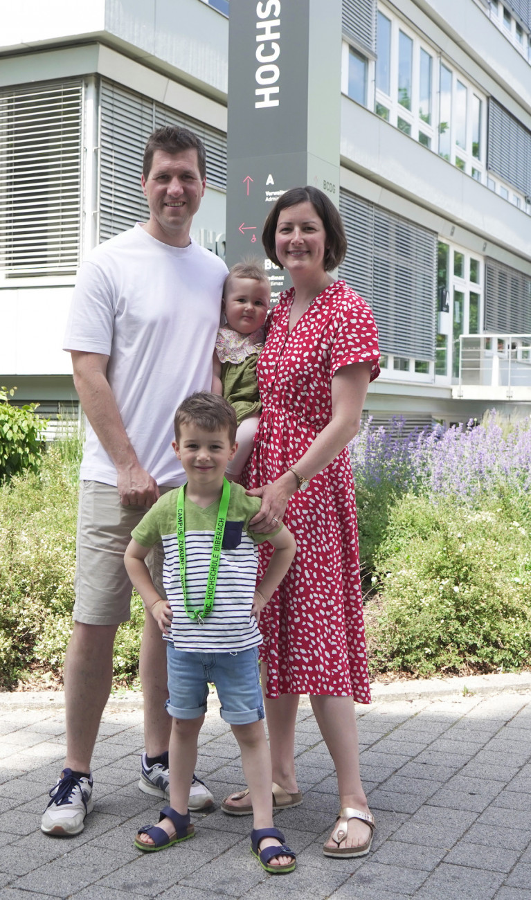 Mann, Frau und zwei Kinder vor Gebäude